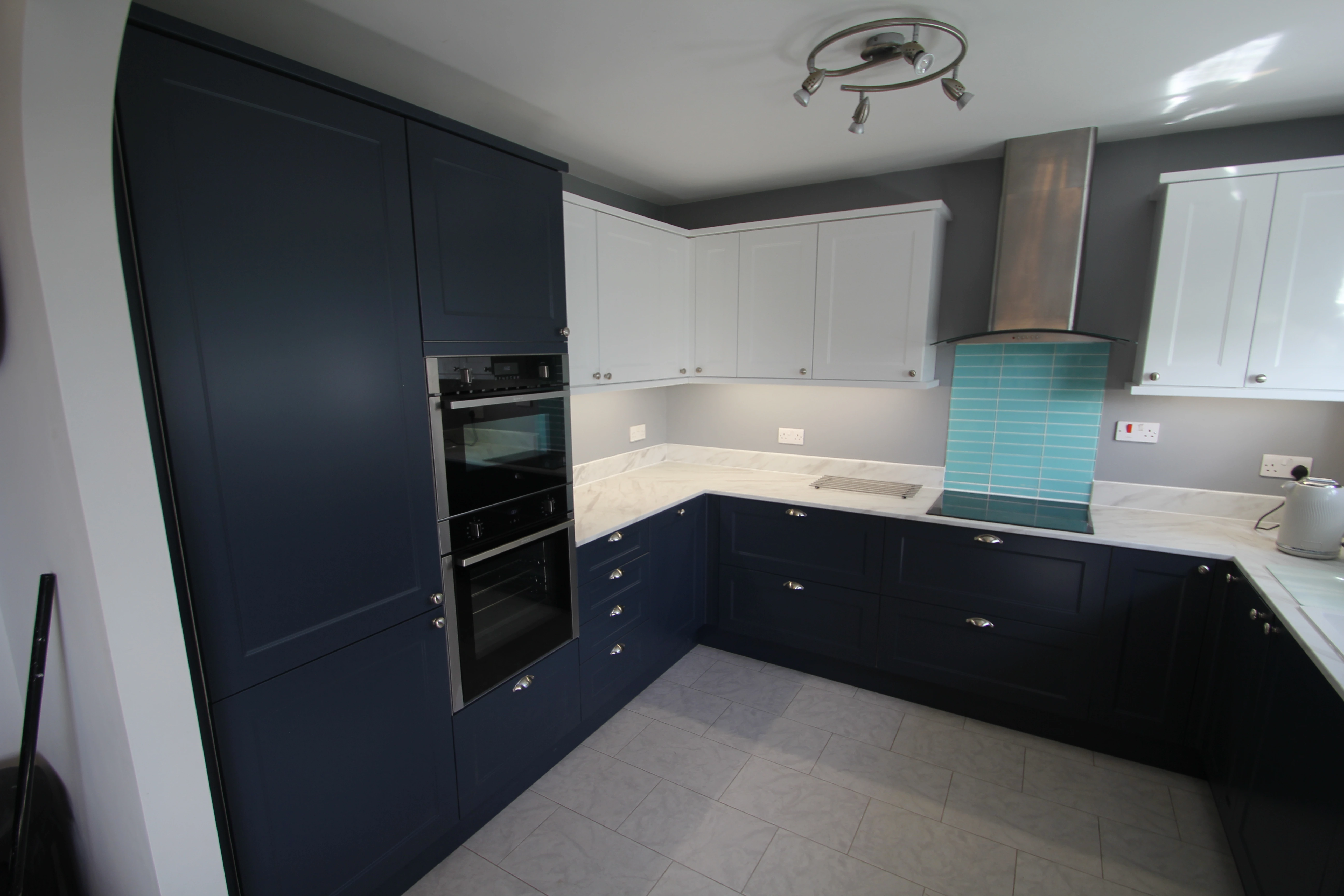 Corner shot of a completed kitchen renovation with a dark blue theme